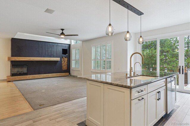 kitchen featuring a sink, stone countertops, ceiling fan, light wood-style flooring, and healthy amount of natural light