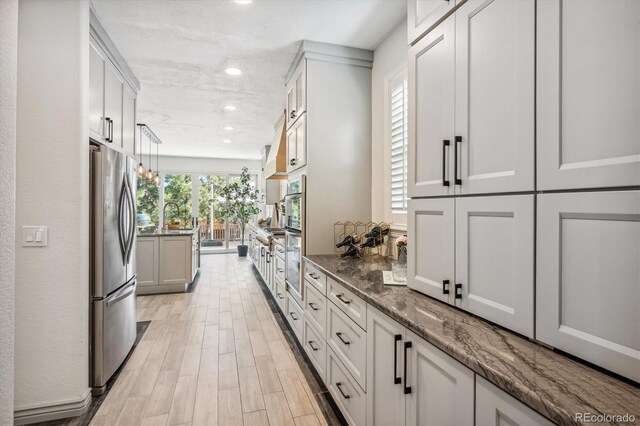 hall featuring light wood-type flooring, recessed lighting, and a sink