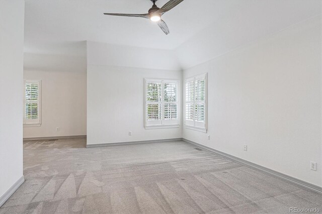 carpeted empty room featuring a ceiling fan, baseboards, and vaulted ceiling
