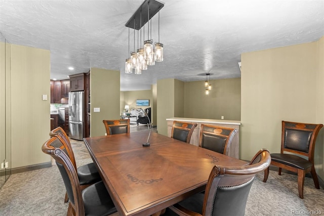 carpeted dining space featuring a textured ceiling