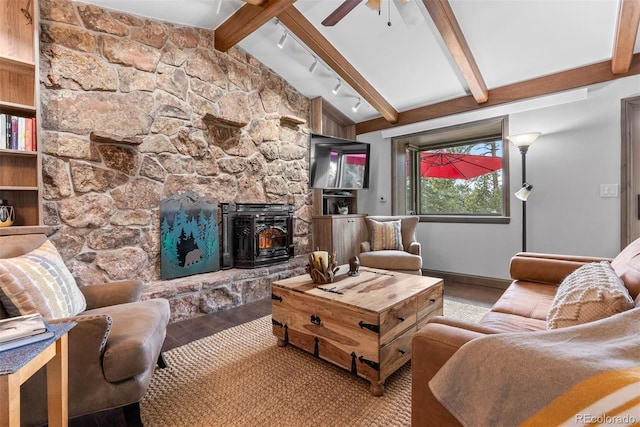 living room featuring hardwood / wood-style floors, lofted ceiling with beams, rail lighting, a wood stove, and ceiling fan