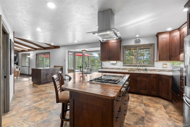 kitchen with a kitchen bar, sink, island range hood, a kitchen island, and backsplash