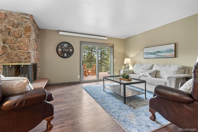 living room with a stone fireplace and hardwood / wood-style floors