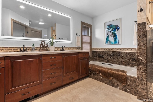 bathroom with tiled tub, vanity, and tile patterned floors