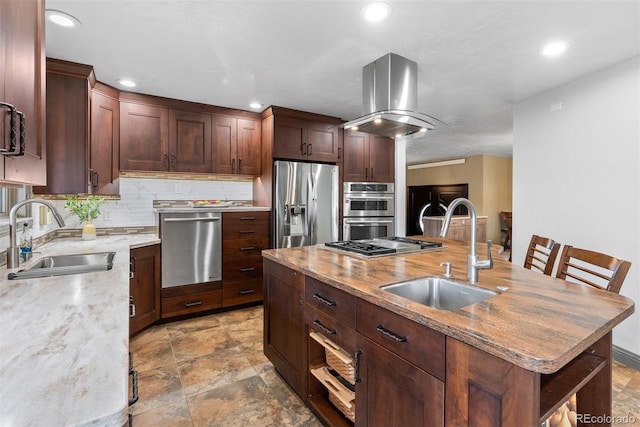 kitchen with appliances with stainless steel finishes, sink, a kitchen island with sink, and tasteful backsplash