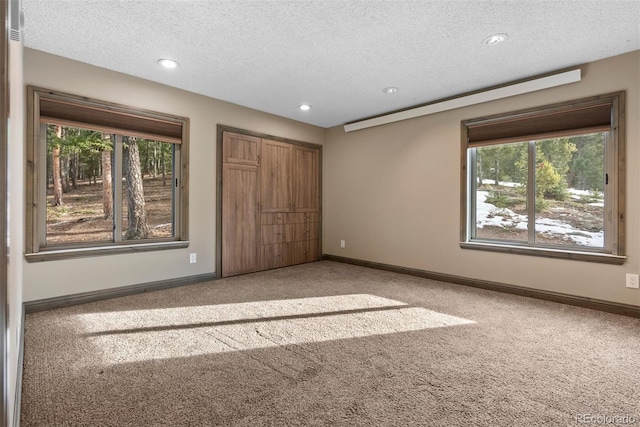 unfurnished bedroom featuring light carpet, a closet, and a textured ceiling