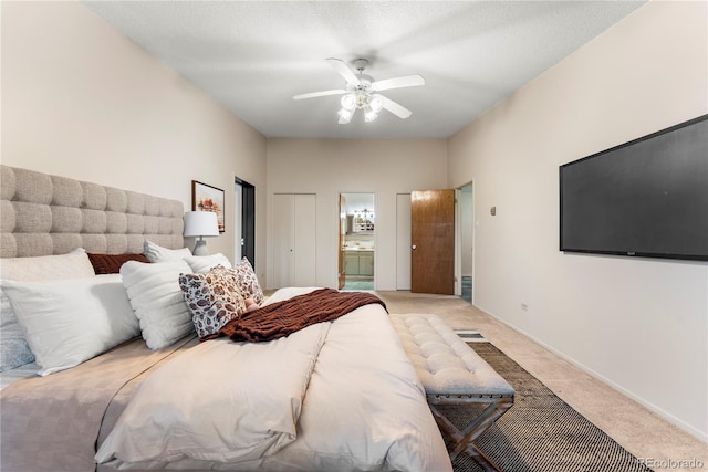 bedroom with ensuite bathroom, a textured ceiling, ceiling fan, and light carpet