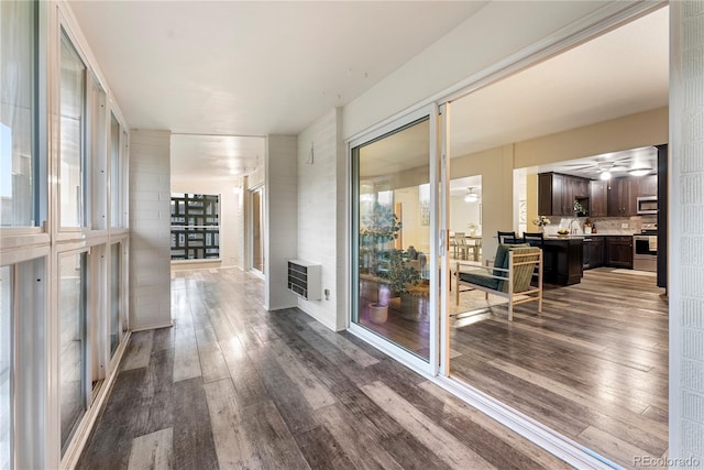 hallway with dark wood-type flooring and heating unit