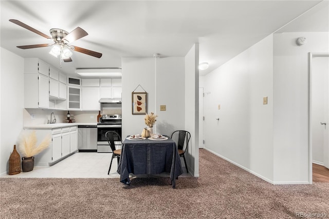 kitchen featuring sink, appliances with stainless steel finishes, white cabinetry, ceiling fan, and light colored carpet