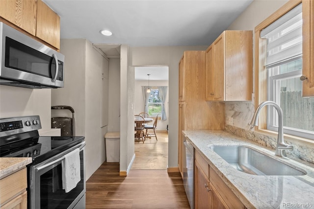 kitchen featuring appliances with stainless steel finishes, a sink, dark wood-type flooring, light stone counters, and recessed lighting