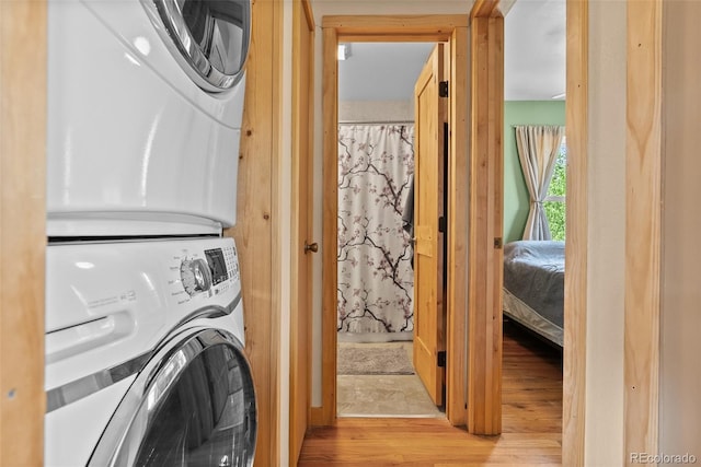 clothes washing area featuring stacked washing machine and dryer and wood finished floors