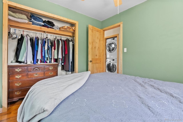 bedroom with stacked washer / dryer, a closet, and wood finished floors