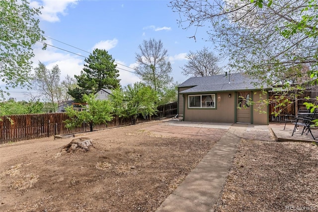 back of property featuring a fenced backyard, a patio area, and a shingled roof