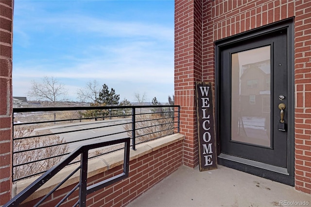 entrance to property featuring brick siding and a balcony