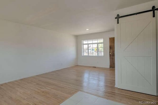 spare room with a barn door and light wood-type flooring