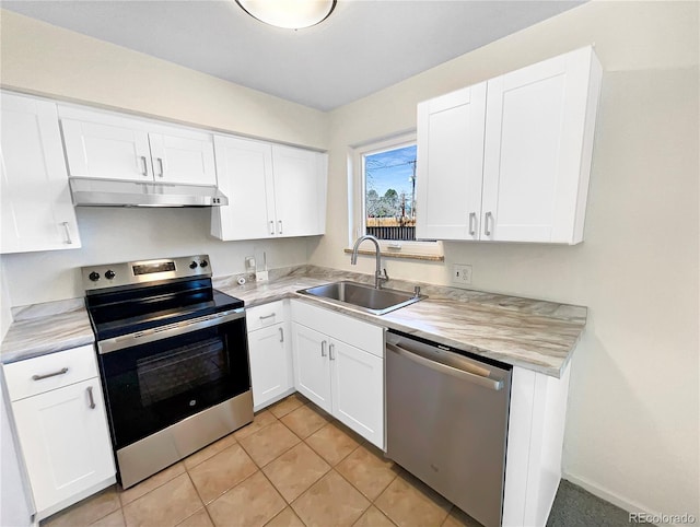 kitchen with under cabinet range hood, light countertops, appliances with stainless steel finishes, and a sink