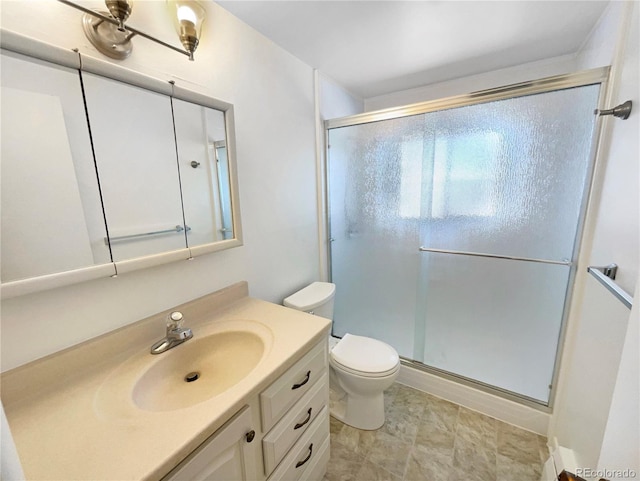 bathroom featuring toilet, a stall shower, and vanity