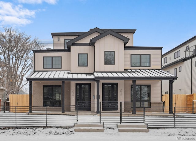 view of front of home featuring a standing seam roof, a fenced front yard, a porch, and board and batten siding