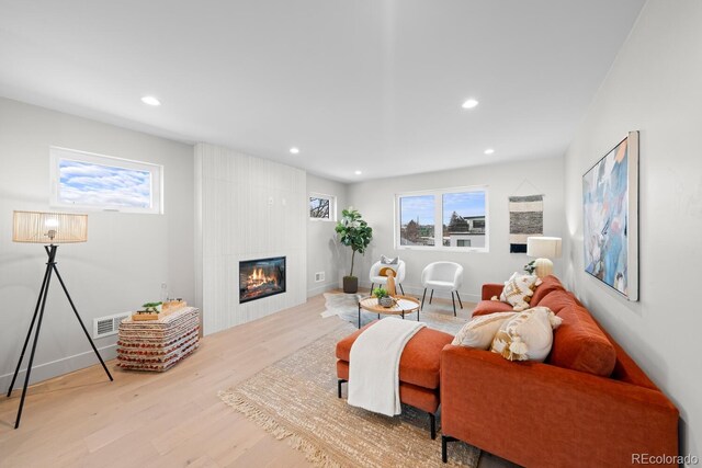 living room with light wood-style floors, baseboards, a tiled fireplace, and recessed lighting