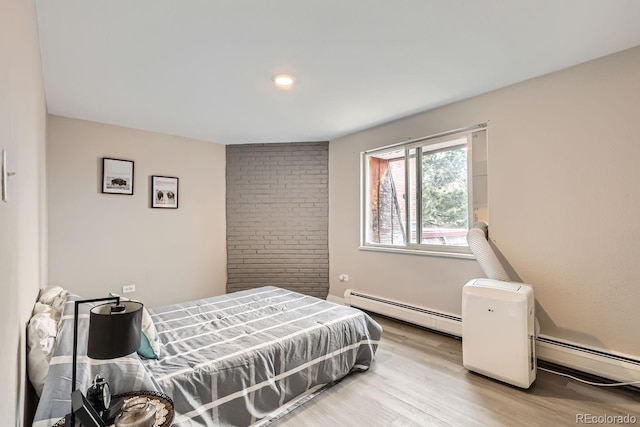 bedroom with light hardwood / wood-style floors and baseboard heating