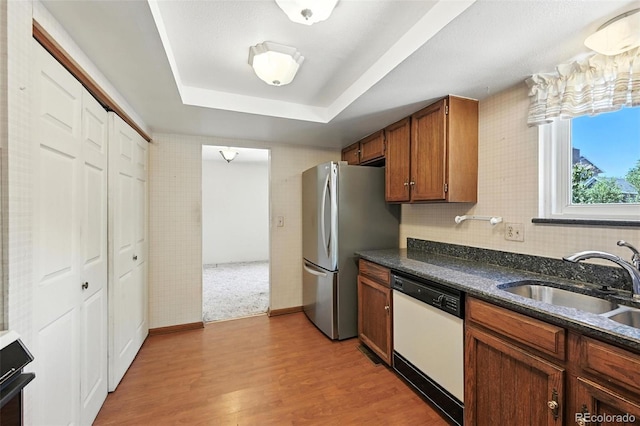 802 Altair Dr, Littleton, CO 80124 - kitchen featuring dishwasher, freestanding refrigerator, brown cabinetry, light wood finished floors, and a tray ceiling