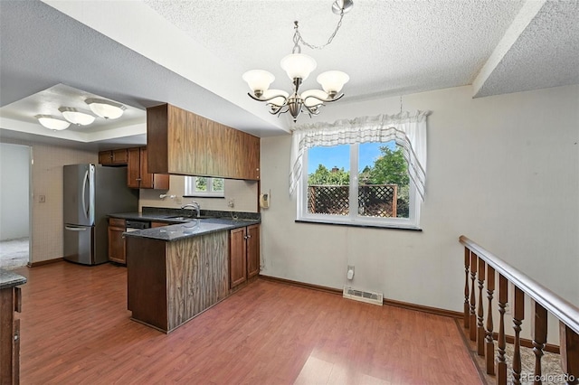 802 Altair Dr, Littleton, CO 80124 - kitchen featuring a peninsula, freestanding refrigerator, a chandelier, a textured ceiling, and dark countertops