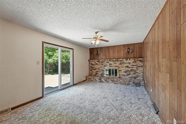 802 Altair Dr, Littleton, CO 80124 - unfurnished living room with wood walls, a ceiling fan, carpet floors, a textured ceiling, and a brick fireplace