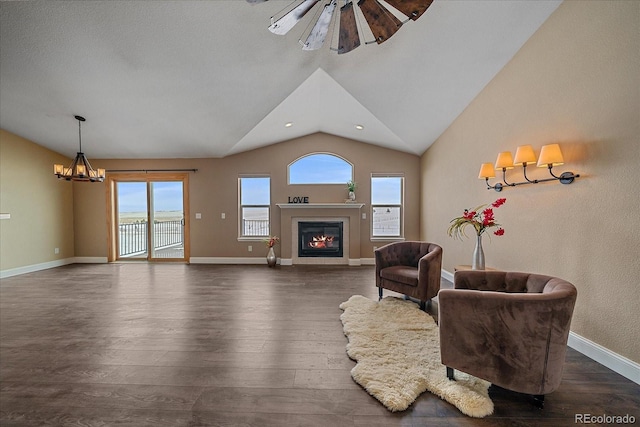 living area featuring dark wood-type flooring, lofted ceiling, and ceiling fan with notable chandelier