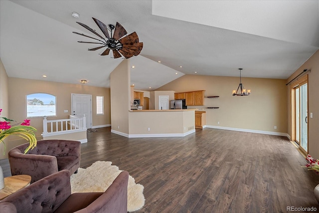 unfurnished living room featuring lofted ceiling, a notable chandelier, dark wood-type flooring, and plenty of natural light