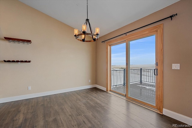 spare room with a water view, dark hardwood / wood-style flooring, and an inviting chandelier