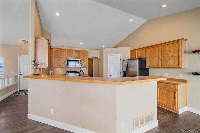 kitchen with a kitchen island, vaulted ceiling, appliances with stainless steel finishes, and dark hardwood / wood-style flooring