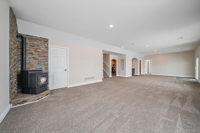 unfurnished living room featuring carpet floors and a wood stove