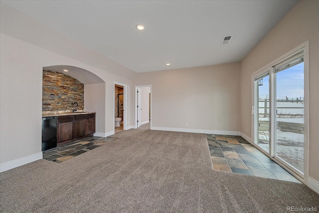 unfurnished living room featuring wet bar and carpet