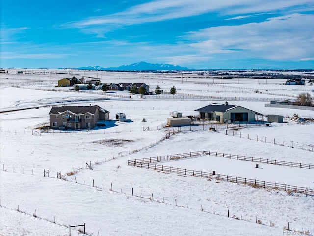 snowy aerial view featuring a mountain view and a rural view