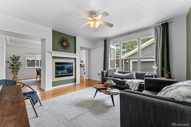 living room featuring ceiling fan, light hardwood / wood-style floors, and a tile fireplace