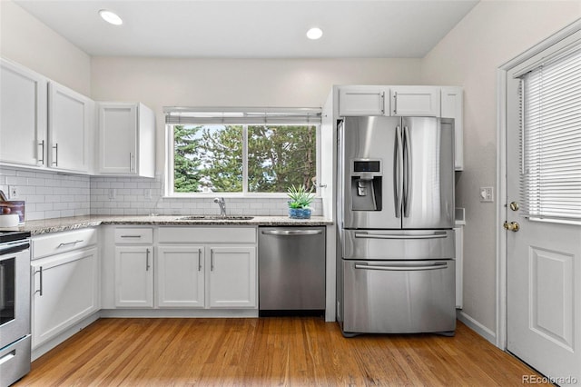 kitchen featuring backsplash, light hardwood / wood-style flooring, white cabinetry, and stainless steel appliances