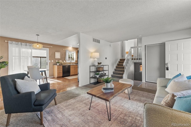 living area featuring stairs, a textured ceiling, and visible vents