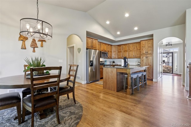 3125 Brunner Blvd, Johnstown, CO 80534 - kitchen featuring stainless steel appliances, arched walkways, a center island, brown cabinets, and a kitchen bar