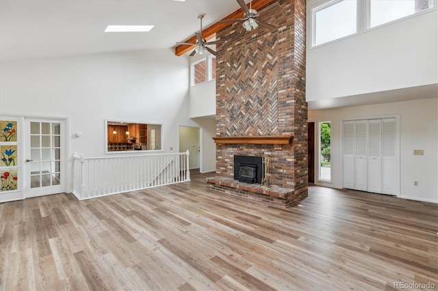 11254 E Colorado Dr, Aurora, CO 80012 - unfurnished living room featuring high vaulted ceiling, a ceiling fan, wood finished floors, a skylight, and a wood stove