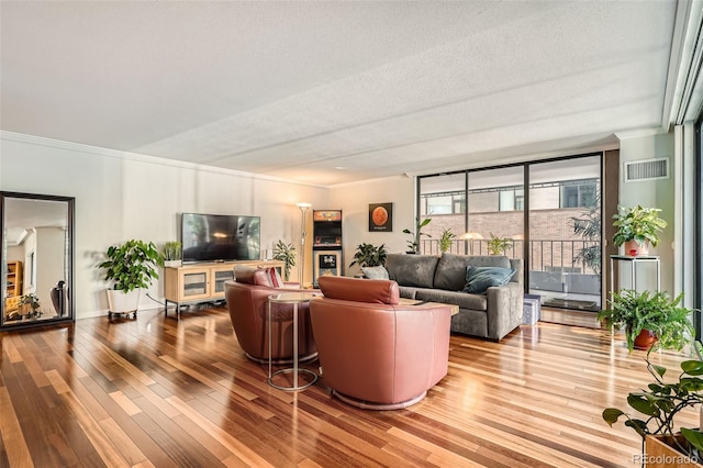 living room featuring crown molding, a textured ceiling, and light wood-type flooring