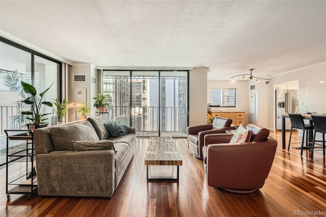 living room with hardwood / wood-style flooring, ornamental molding, expansive windows, and a textured ceiling