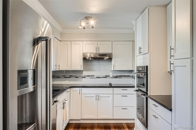 kitchen with backsplash, stainless steel appliances, ornamental molding, white cabinets, and dark hardwood / wood-style flooring