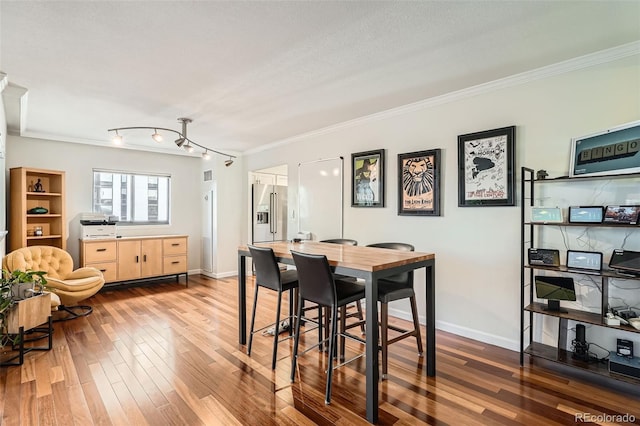 dining space with crown molding, hardwood / wood-style flooring, and a textured ceiling