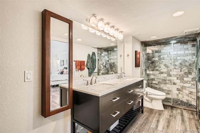 bathroom with a shower with door, vanity, hardwood / wood-style floors, and a textured ceiling