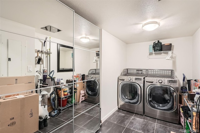 laundry room with washing machine and dryer, dark tile patterned flooring, and a textured ceiling