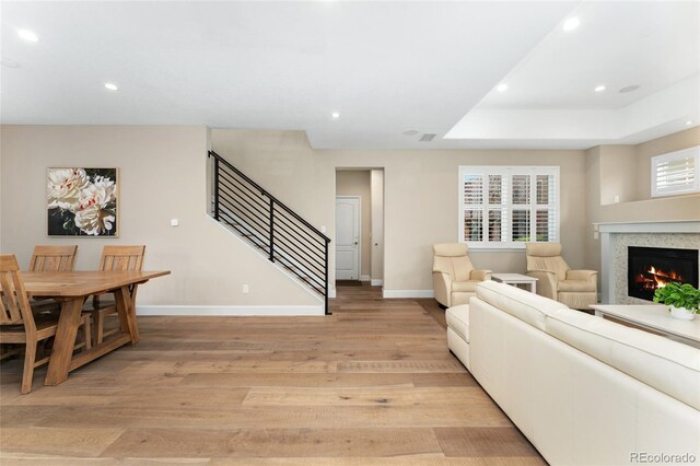 10618 Clearview Ln, Highlands Ranch, CO 80126 - living room featuring light wood-style floors, stairs, baseboards, a warm lit fireplace, and recessed lighting