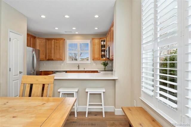 10618 Clearview Ln, Highlands Ranch, CO 80126 - kitchen with recessed lighting, appliances with stainless steel finishes, tasteful backsplash, light wood-style floors, and glass insert cabinets
