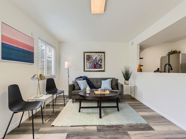 living area featuring visible vents, baseboards, and wood finished floors