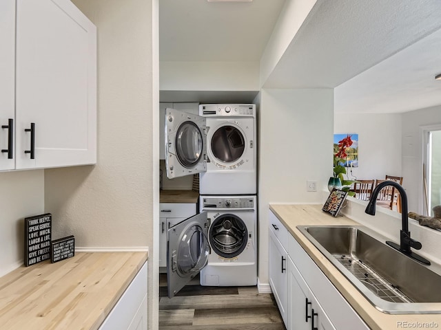 laundry area featuring a sink, wood finished floors, and stacked washer / dryer