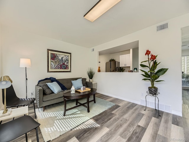 living area featuring wood finished floors, baseboards, and visible vents